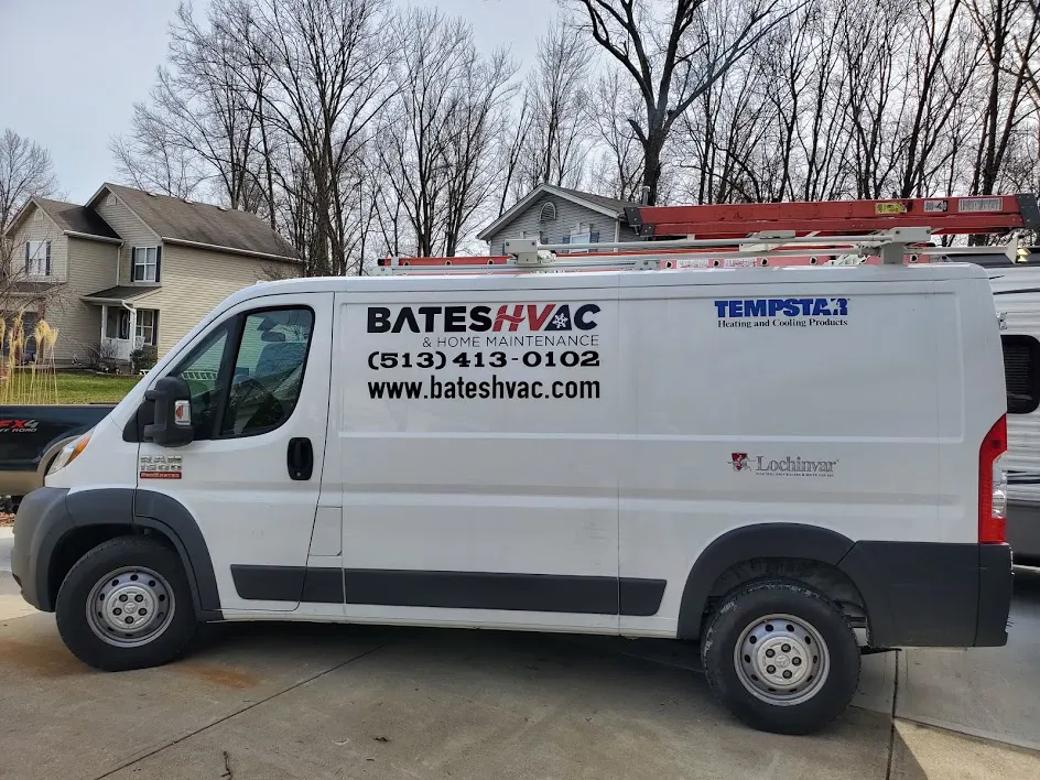 A white Bates HVAC Ram ProMaster van with the phone number and website on the side, parked on a residential street